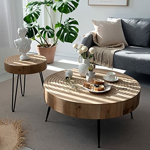 Stylish living room with round wooden coffee tables, a bust statue, and a cozy sofa.