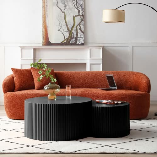 Stylish living room with orange sofa, black coffee tables, and wall art.