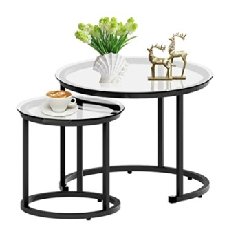 Two nesting coffee tables with white tops and black legs, decorated with a plant, deer figurines, and a cup of coffee.